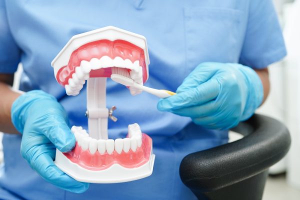 dentist showing patient how to clean dentures